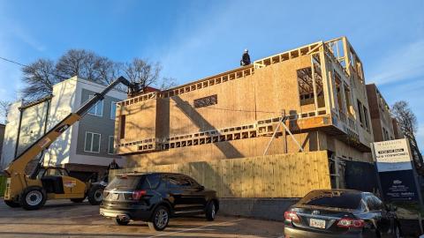 A photo of a large new townhome community being built beside two wide roads.