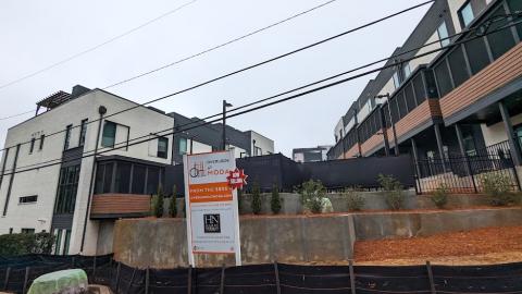 A photo of a large townhome development site under gray skies with tall white and black modern townhomes for sale. 
