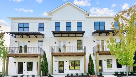 A new development of white three-story townhomes with white modern interiors on the Westside of Atlanta under blue skies.