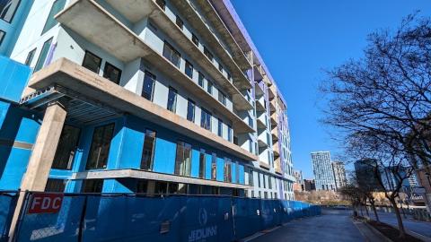 A photo of a large concrete new building beside a highway under blue skies in Atlanta. 
