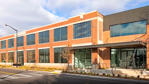A photo of a two-story brick building with open white interiors and a rooftop deck that's now an office where Coke once did bottling.