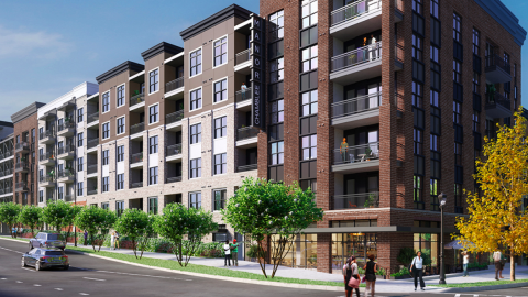 An image showing a new brick clad apartment building with shops at the base that's taken shape under blue skies near two wide streets in Chamblee, north of Atlanta.