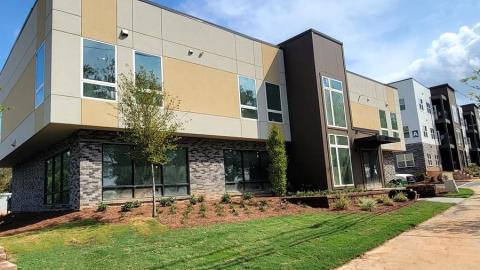 A modern-style new building with affordable housing and a brown and gray exterior under blue skies. 