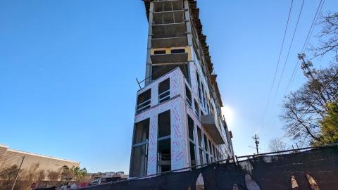 An image showing a large pie-shaped new building under blue skies being built beside some railroad tracks in Atlanta.