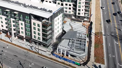 An image of a large white and gray development on a corner in Atlanta near two wide streets. 