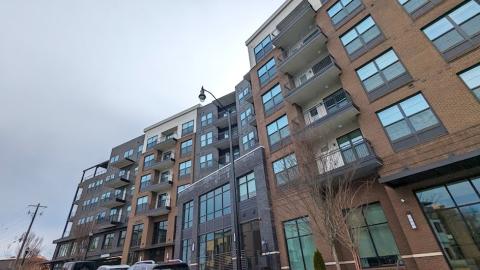 An image of a large brick and glass new apartment complex with a pool in the middle and white walls and a gym and pet spa inside.