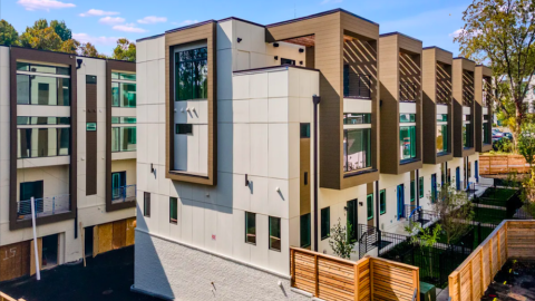 A photo of modern townhomes with white and brown exteriors under blue skies in Atlanta. 