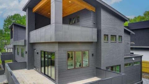 A photo showing a modern style black-painted duplex home with three levels under blue skies in Atlanta. 