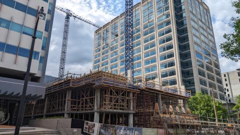 The base floors of a new tower have been poured near a busy street in Atlanta under blue cloudy skies. 