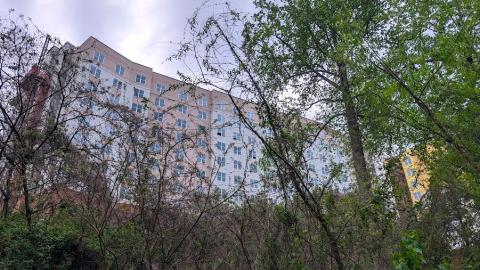An image of a new 11-story building with gray and white siding standing over streets and a dirt exercise trail in Atlanta. 