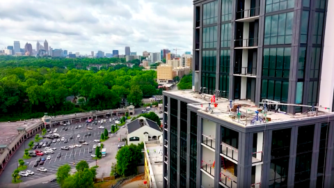 A photo of a black and white condo tower over a large road and shopping center in Atlanta under blue-gray skies.