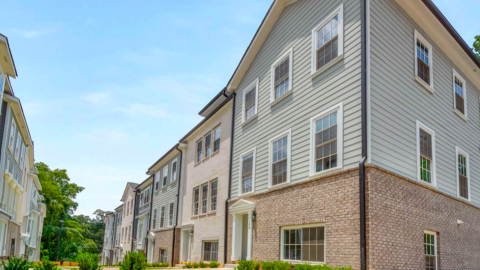An image showing a new siding and brick townhome development on Atlanta's southside with white modern interiors and many windows, with three stories. 