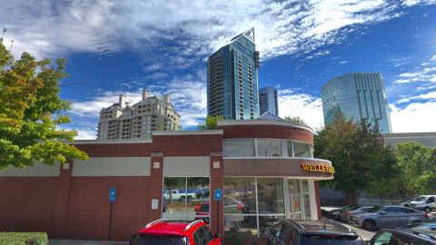 An image showing a former brick bank branch under blue skies surrounded by many towers and trees in Atlanta.