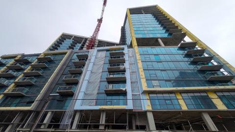 A photo of a high-rise building with much glass under construction with many balconies and a red crane in Buckhead Atlanta.