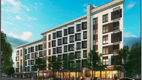 An image of a  large white and brown affordable housing project underway in Atlanta along two wide streets under blue skies. 