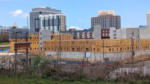 A photo of a large construction project made of wood under blue skies near wide streets.