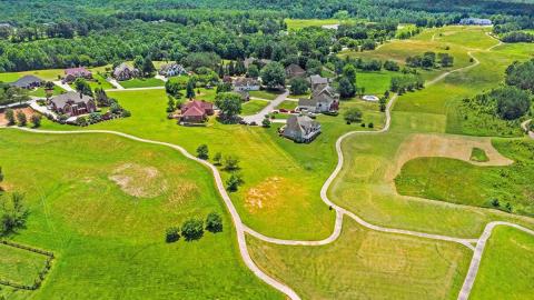 A photo of a large green former golf course where duplex-style homes are being build near active golf and many trees north of Atlanta.